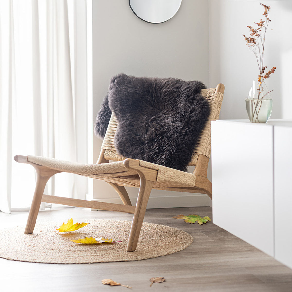The Autumn Sale at Sheepskinhouse: a dark sheepskin over a lounge chair with yellow leaves on a jute rug