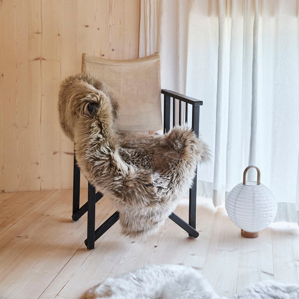 Sheepskin rug draped over a black chair in a bright wooden room