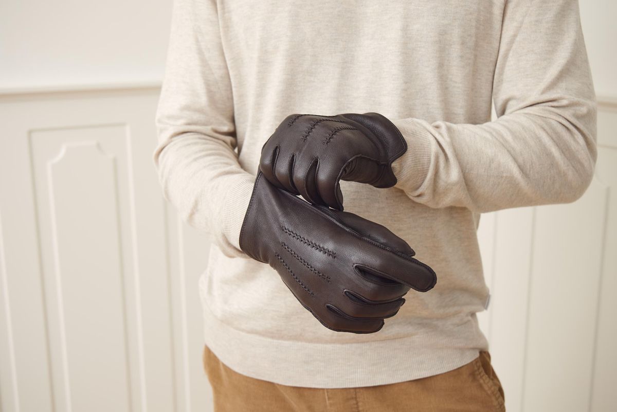 Man pulling on dark brown deerskin leather gloves