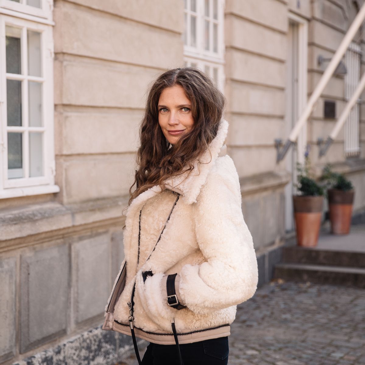 Woman in a cream shearling jacket on a city street