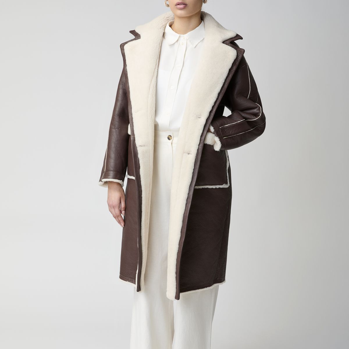 Woman in a dark brown shearling coat with a cream collar