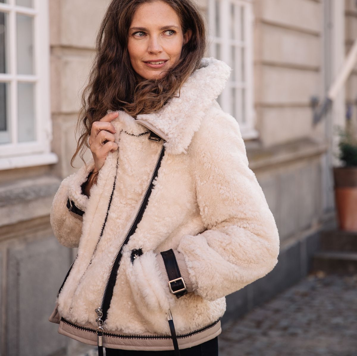 Woman in a cream shearling jacket on a city street