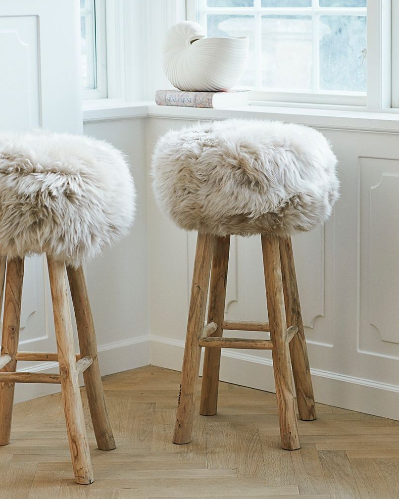 Theo bar stools with pale New Zealand long hair covers by a bright window
