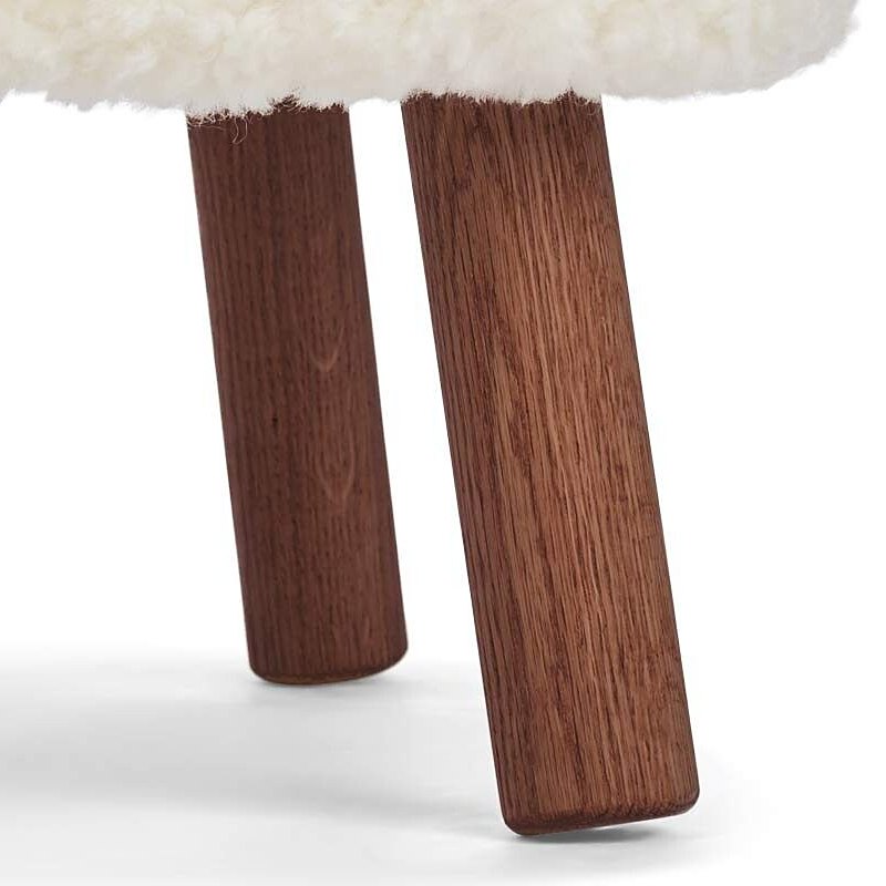 Detail of two walnut legs under an ivory short hair seat