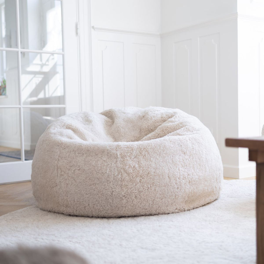 Cream short hair sheepskin bean bag on a white rug in a bright room