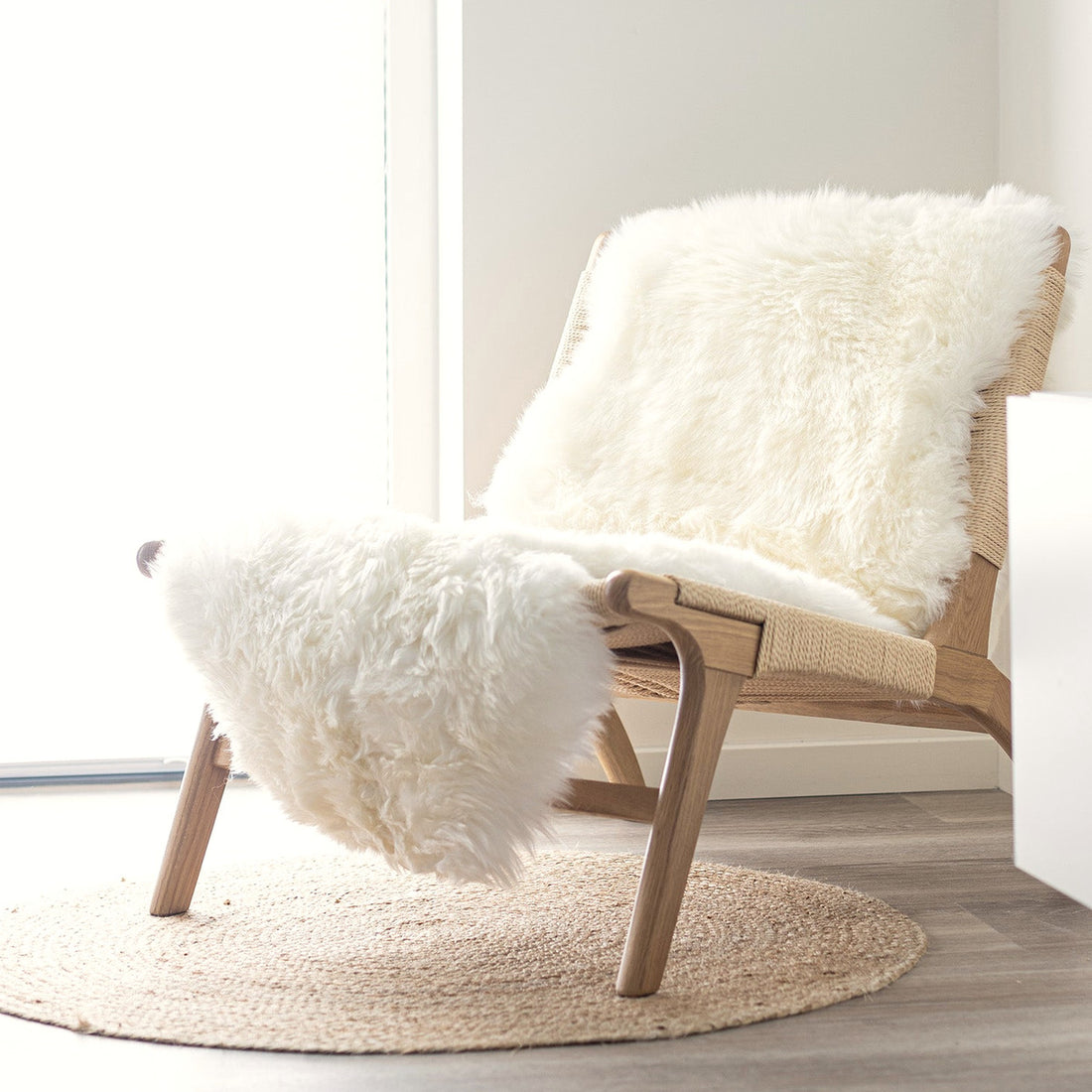 Ivory long hair sheepskin on an oak lounge chair in a bright white room