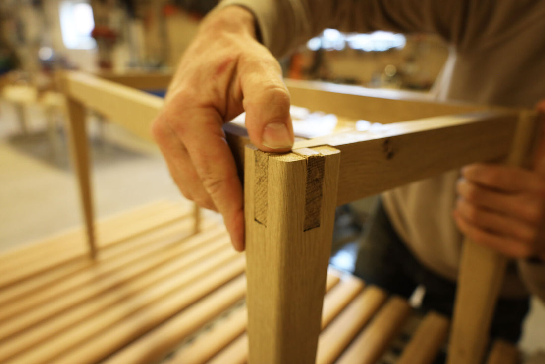 Joiner assembling an oak bench frame in the workshop in Denmark